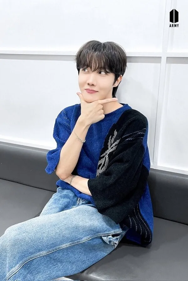 Ảnh j-hope cute có một chàng trai trẻ ngồi trên ghế dài với cằm