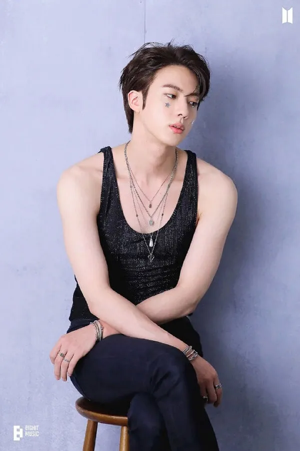 Ảnh jin bts đẹp có một người đàn ông ngồi trên chiếc ghế đẩu mặc xe tăng màu đen