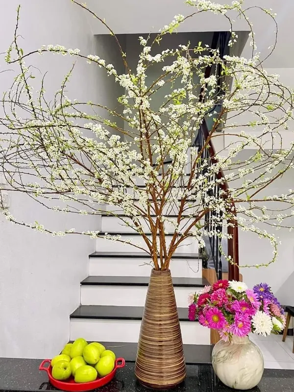 Có một chiếc bình số hoa trong đó trên bàn